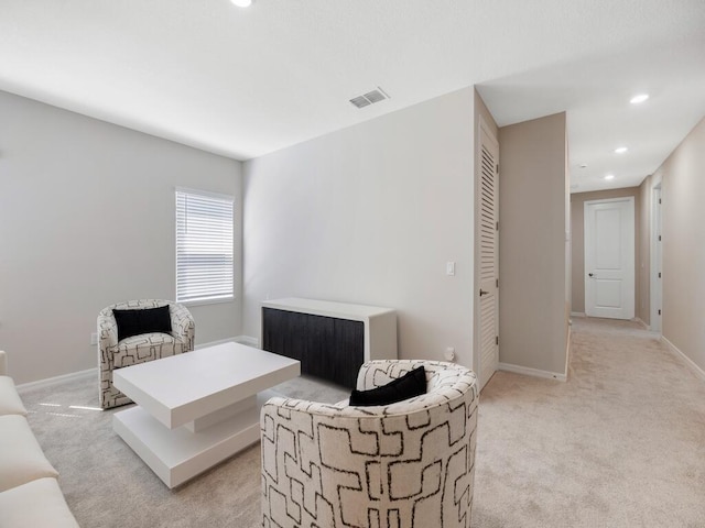 living room featuring recessed lighting, light colored carpet, visible vents, and baseboards