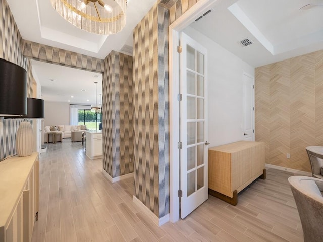 bathroom with wood finish floors, visible vents, wallpapered walls, baseboards, and an accent wall