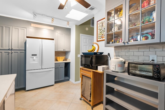 kitchen with visible vents, a ceiling fan, white refrigerator with ice dispenser, black microwave, and light countertops