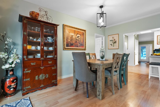 dining space with light wood-style flooring, baseboards, and ornamental molding