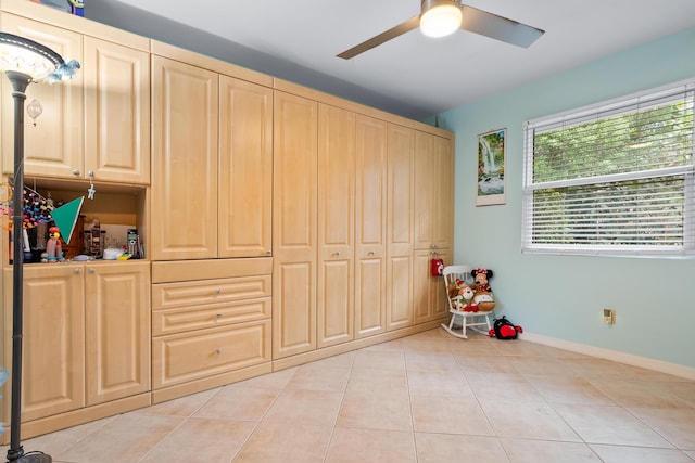 interior space with baseboards, light tile patterned flooring, and a ceiling fan