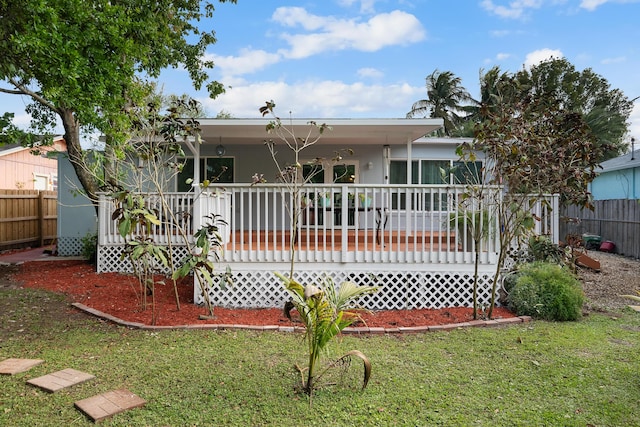 rear view of house featuring a yard, fence, and a wooden deck