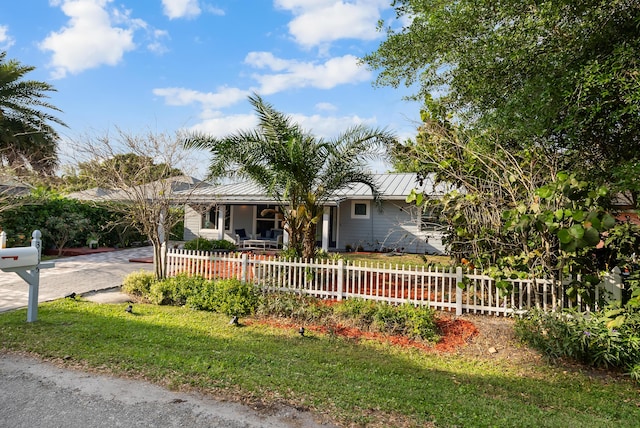 ranch-style house with a standing seam roof, driveway, a fenced front yard, and metal roof