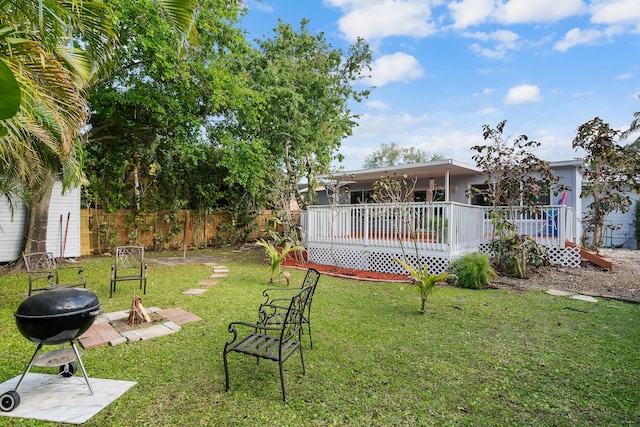 view of yard featuring an outdoor fire pit, a deck, and fence