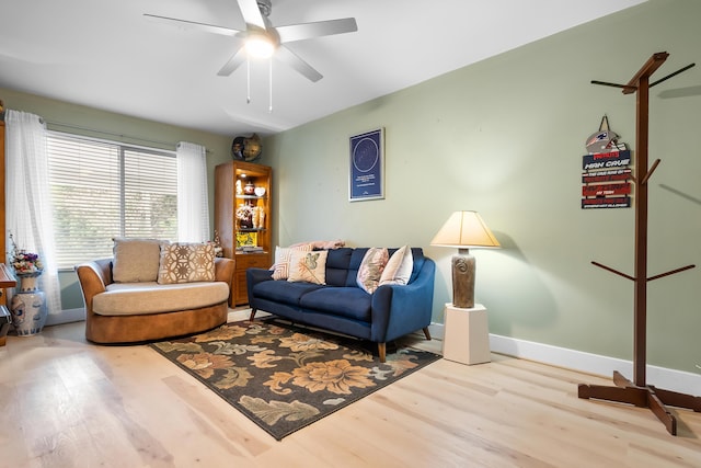 living area featuring baseboards, wood finished floors, and a ceiling fan