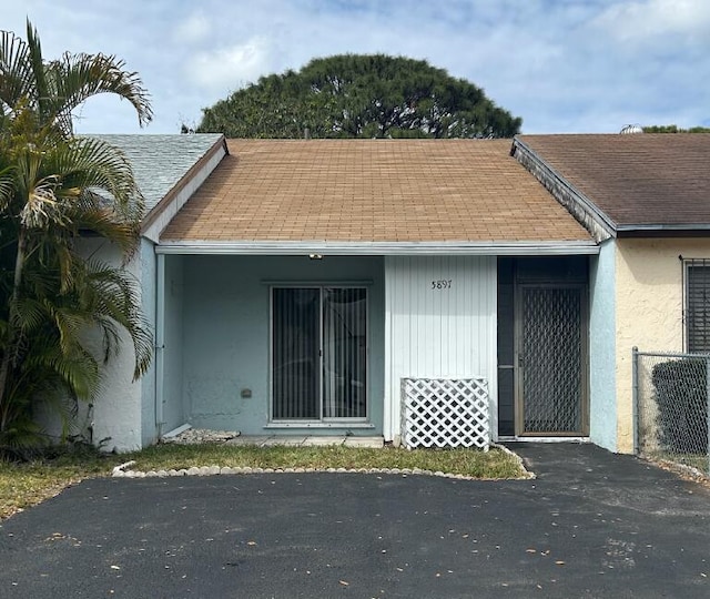 property entrance featuring stucco siding and roof with shingles