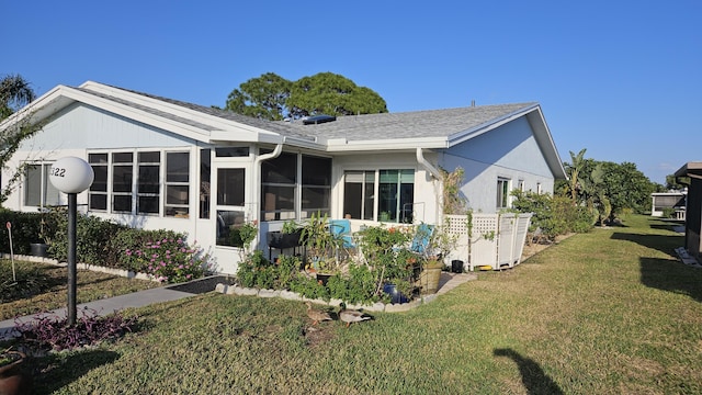 rear view of house with a yard, a sunroom, and stucco siding