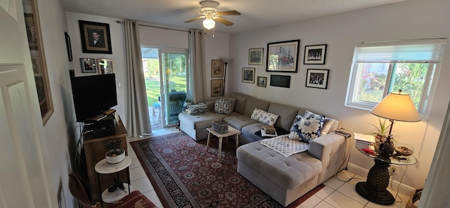 living area with tile patterned floors, a ceiling fan, baseboards, and a textured ceiling