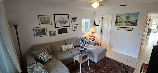 tiled living room featuring visible vents, baseboards, a textured ceiling, and ceiling fan