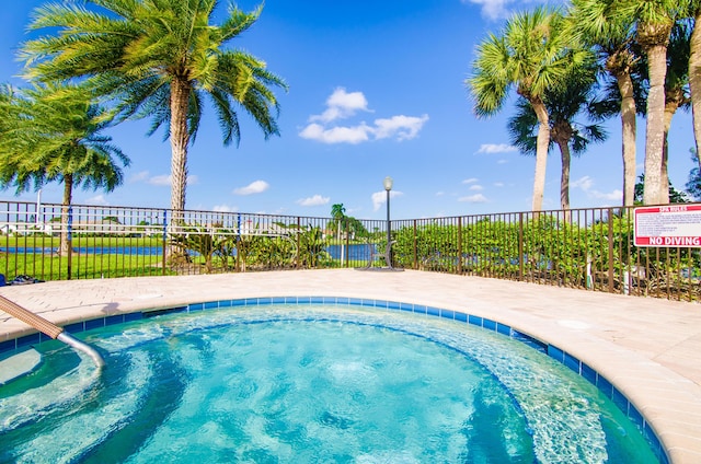 view of pool with fence and a hot tub