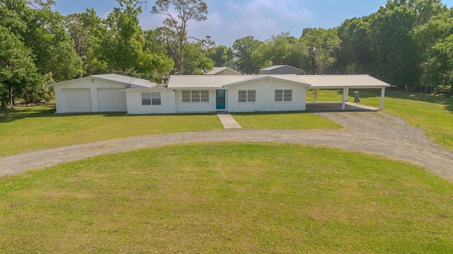 view of front of house with an attached carport, a front yard, stucco siding, metal roof, and driveway