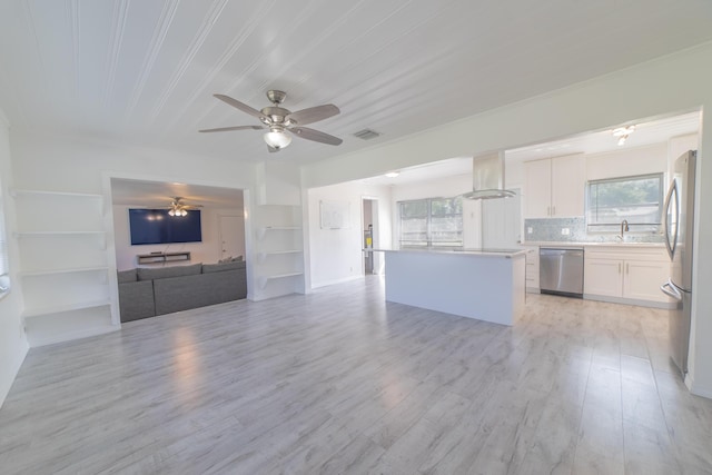 unfurnished living room featuring a sink, visible vents, a wealth of natural light, and a ceiling fan