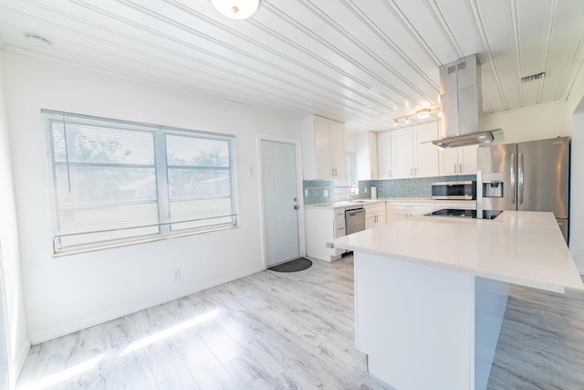 kitchen with light countertops, decorative backsplash, island exhaust hood, stainless steel appliances, and a sink