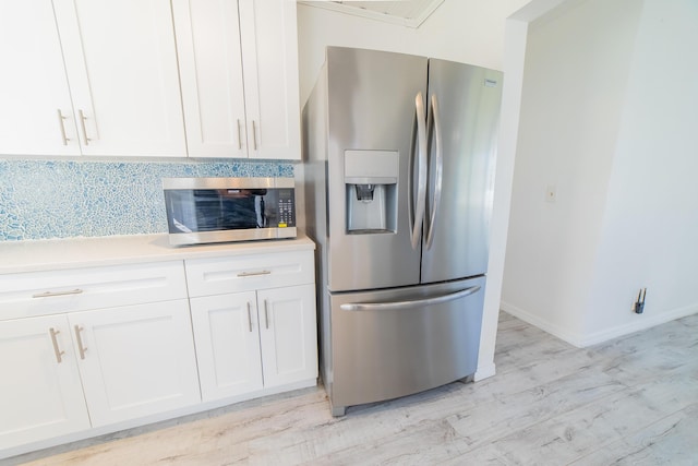 kitchen featuring white cabinetry, stainless steel appliances, light countertops, decorative backsplash, and baseboards