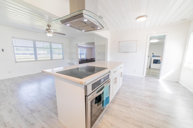 kitchen featuring washer / clothes dryer, range hood, stainless steel oven, black electric stovetop, and ceiling fan