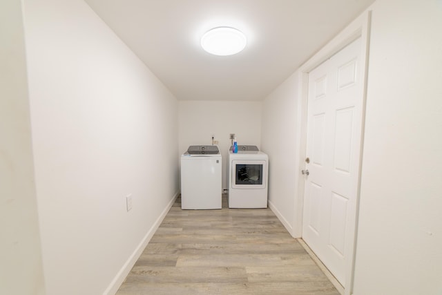 laundry room featuring laundry area, baseboards, light wood-style floors, and separate washer and dryer