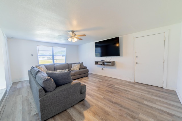 living room featuring light wood-style flooring, a ceiling fan, and baseboards