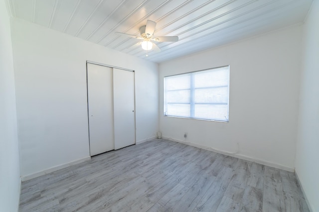 unfurnished bedroom featuring light wood-type flooring, baseboards, a closet, and ceiling fan