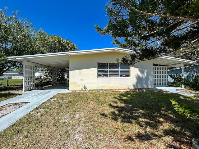 view of side of home with a carport, concrete driveway, and a yard