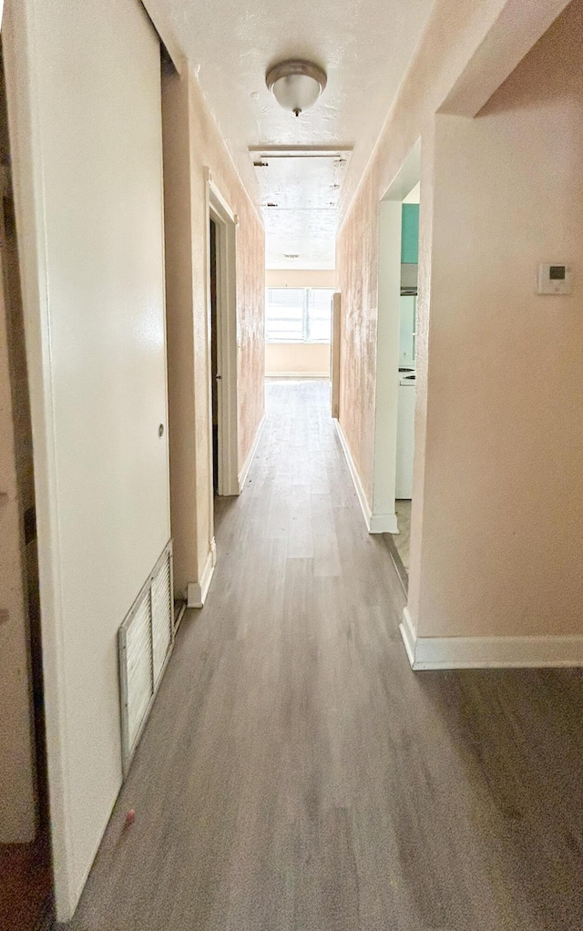 hall featuring wood finished floors, visible vents, and baseboards