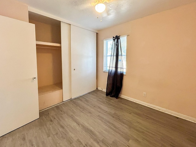 unfurnished bedroom with a closet, baseboards, and wood finished floors