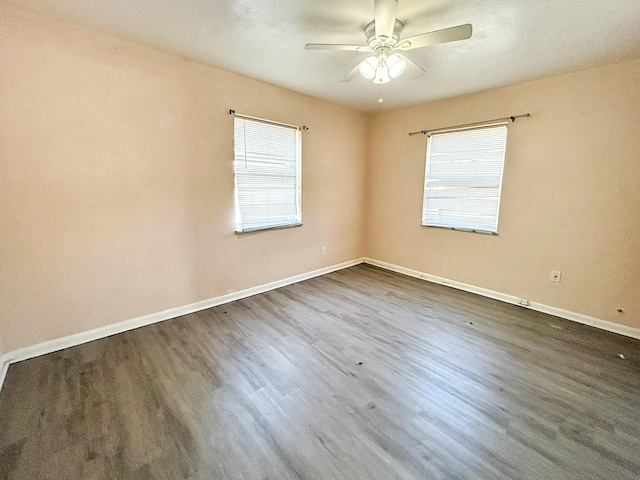 empty room featuring dark wood-style floors, baseboards, and ceiling fan