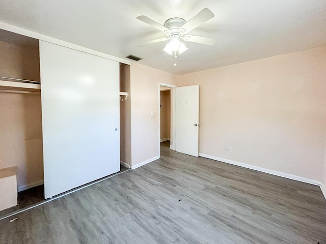 unfurnished bedroom with a ceiling fan, wood finished floors, visible vents, baseboards, and a closet