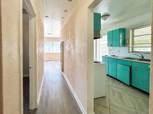 kitchen with baseboards, white range with electric cooktop, a sink, extractor fan, and light wood-type flooring