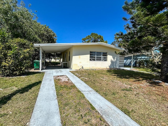 view of front facade featuring an attached carport, concrete driveway, and a front yard