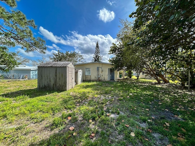 view of yard featuring a storage shed, fence, and an outdoor structure