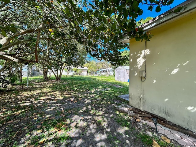 view of yard with an outbuilding, a storage shed, and fence