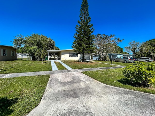 view of front facade with an attached carport, concrete driveway, and a front yard