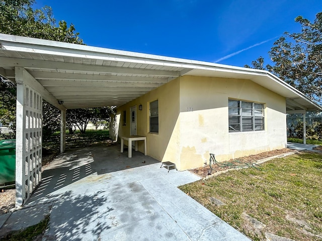 view of property exterior with stucco siding, a carport, and driveway