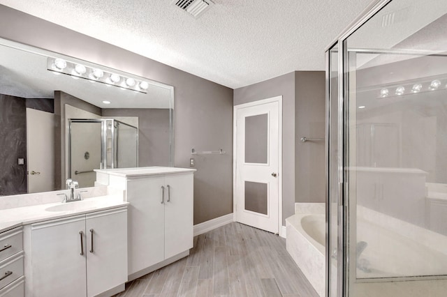 full bath with vanity, visible vents, a stall shower, a textured ceiling, and a bath