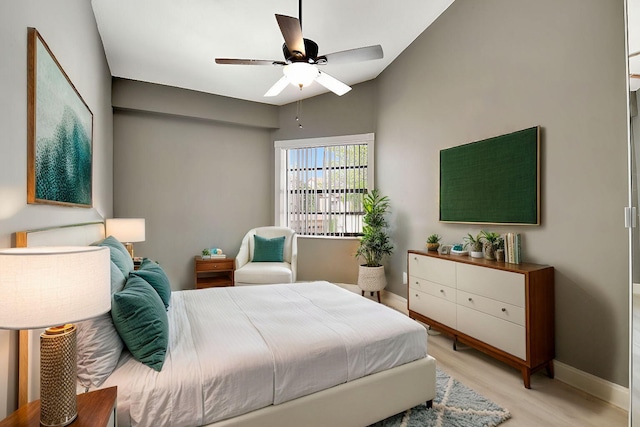 bedroom featuring light wood-type flooring, baseboards, and a ceiling fan