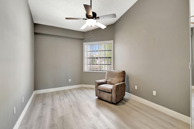 sitting room featuring light wood-style flooring, baseboards, and ceiling fan