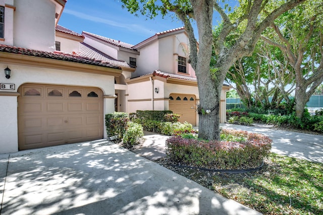 mediterranean / spanish-style house featuring a tile roof, a garage, driveway, and stucco siding