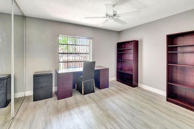 unfurnished office with wood finished floors, a ceiling fan, baseboards, and a textured ceiling