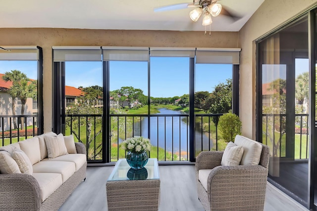 sunroom / solarium featuring a water view and a ceiling fan