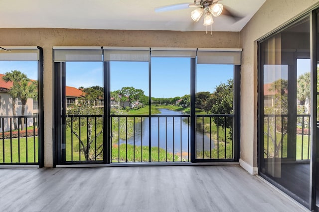 unfurnished sunroom featuring a water view and ceiling fan