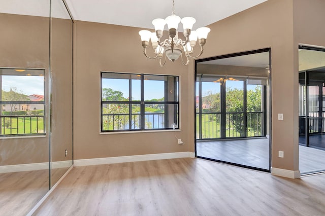 unfurnished dining area featuring a notable chandelier, baseboards, and wood finished floors