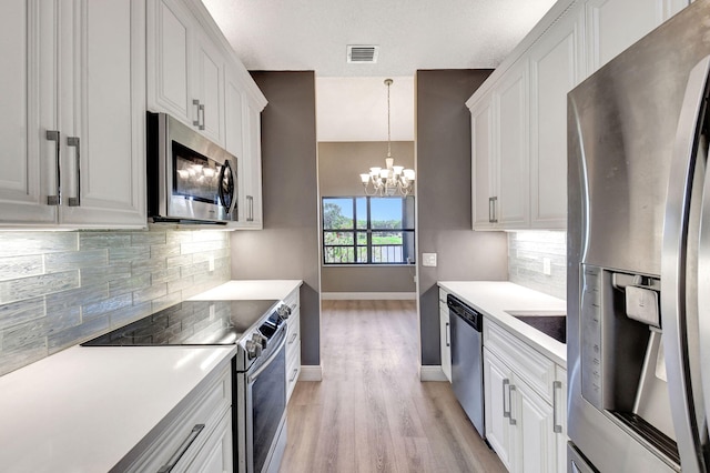 kitchen featuring visible vents, stainless steel appliances, light countertops, white cabinetry, and a chandelier