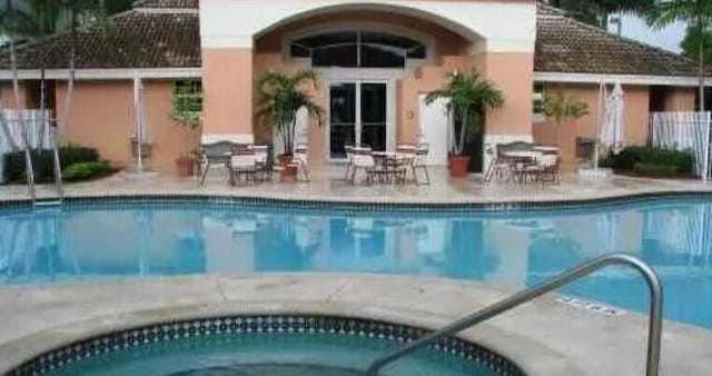 community pool with an outdoor structure and a patio area