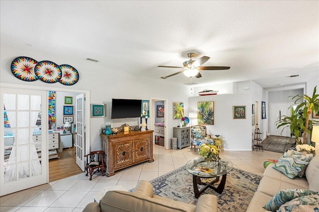 living room with light tile patterned flooring, baseboards, visible vents, and ceiling fan