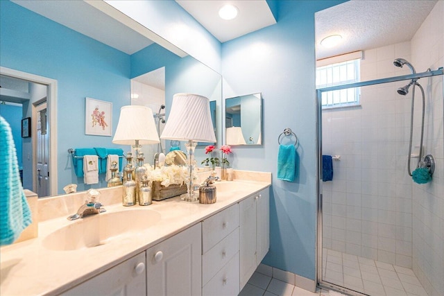 full bathroom featuring a tile shower, double vanity, a textured ceiling, and a sink