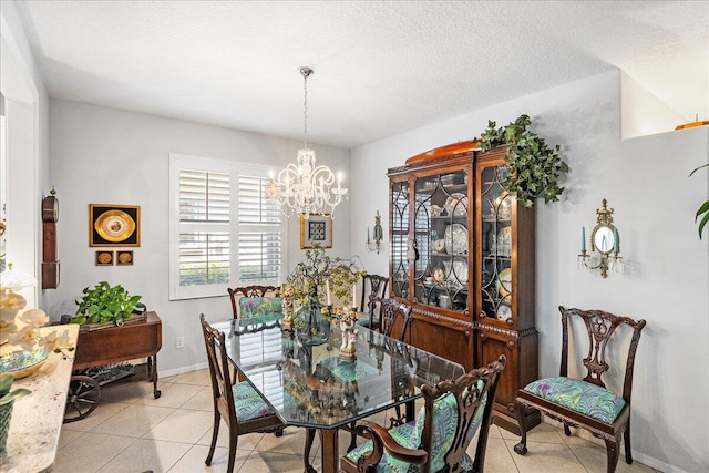 dining space with a notable chandelier, baseboards, light tile patterned floors, and a textured ceiling