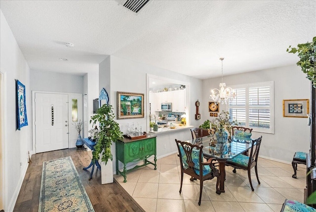 dining space with a notable chandelier, baseboards, light tile patterned floors, and a textured ceiling