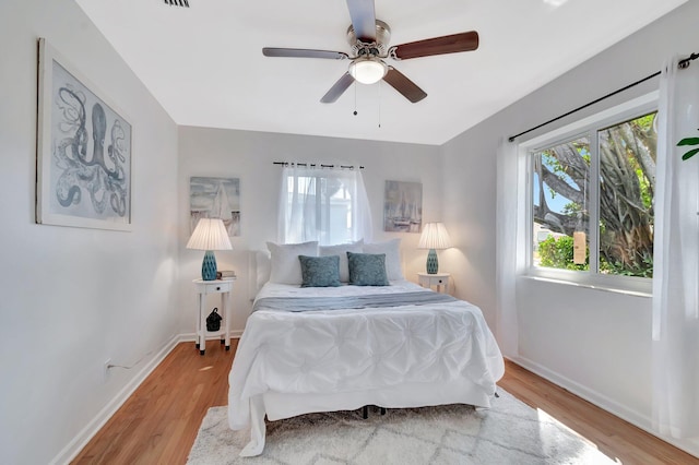 bedroom with a ceiling fan, visible vents, light wood-style floors, and baseboards