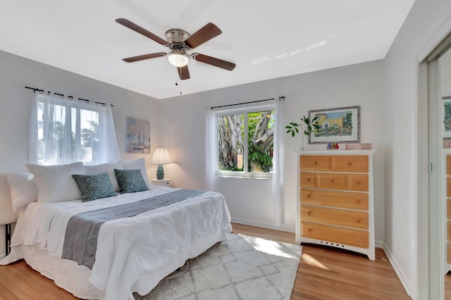 bedroom featuring a ceiling fan, baseboards, and light wood finished floors