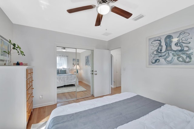 bedroom featuring light wood-type flooring, visible vents, a closet, baseboards, and ceiling fan